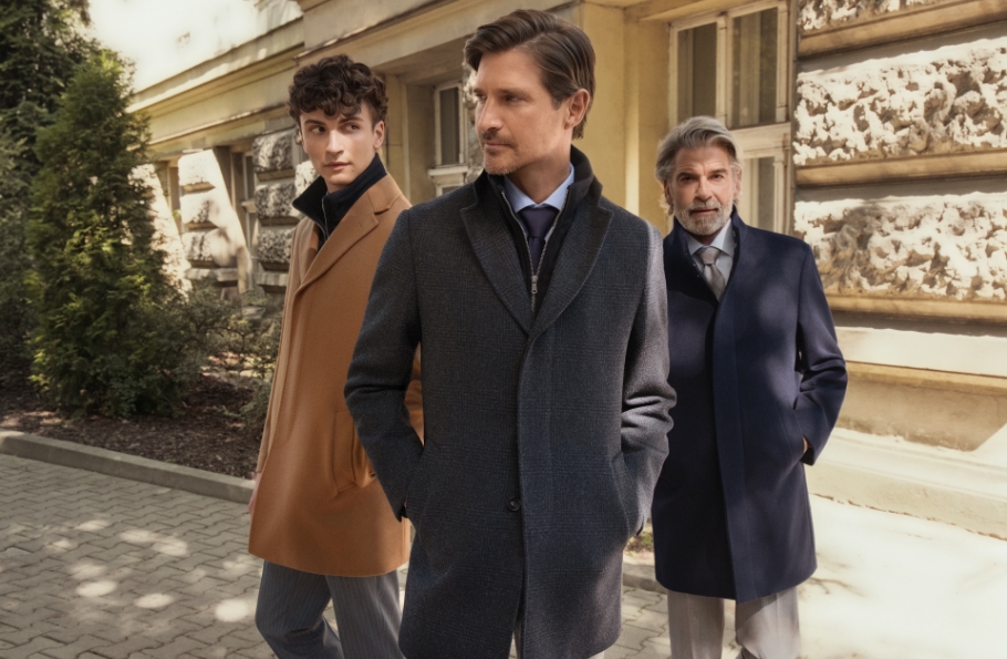 Mężczyźni w płaszczach stojący na tle budynku