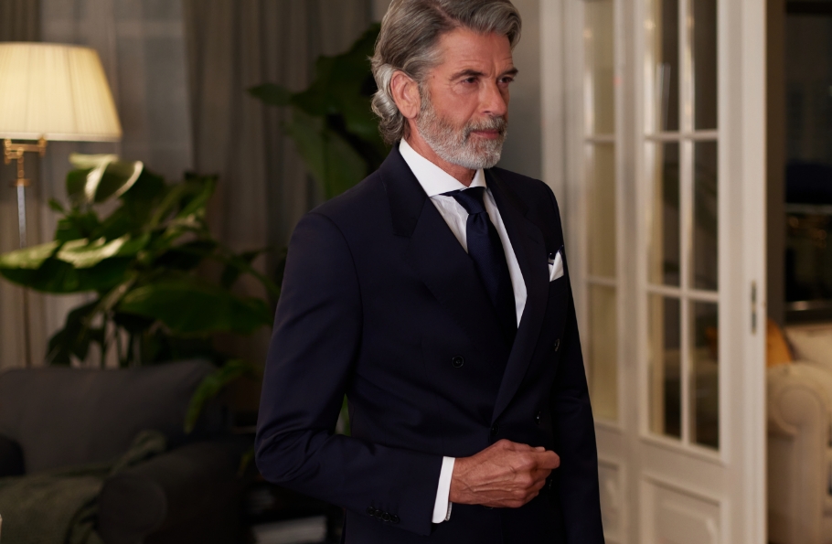 Mężczyzna w granatowym garniturze w eleganckim wnętrzu.