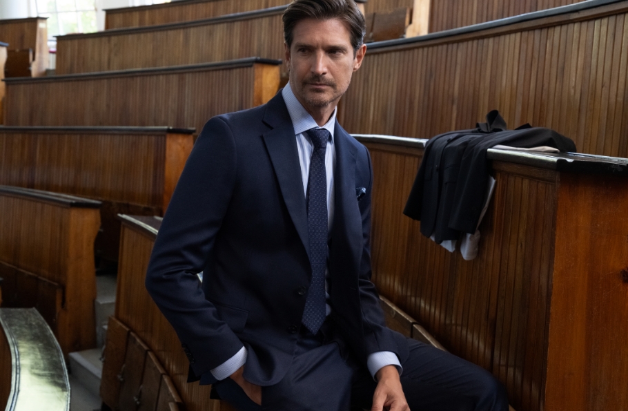 Elegancki mężczyzna w granatowym garniturze Bytom siedzący w auli.