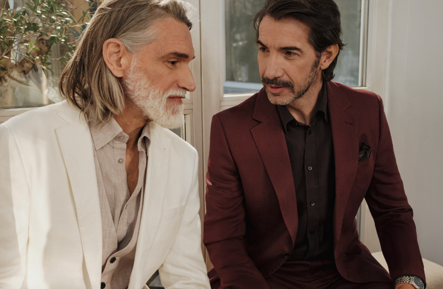 Dwóch dojrzałych mężczyzn w beżowej i bordowej marynarce Bytom siedzących przy oknie.